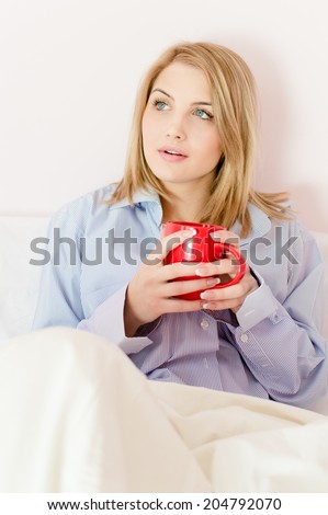 romantic beautiful happy smile young woman in bed holding cup of hot drink or water looking up on white or light wall copy space background closeup portrait picture