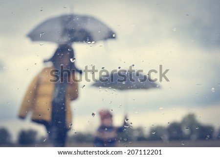 image of mother and son under umbrella silhouette through wet window