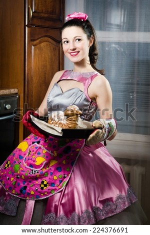 portrait of baking yummy cake charming sincere funny pinup girl in a dress and apron happy smiling and looking at camera