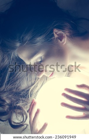 closeup portrait of beautiful young woman holding ball of light and keeping eyes closed