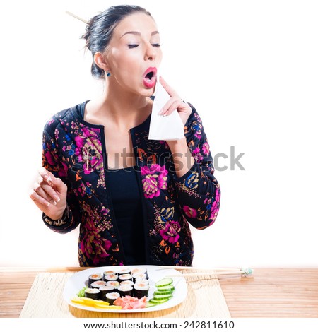 portrait of brunette pretty girl with sushi plate wiping her mouth using napkin isolated on a white background