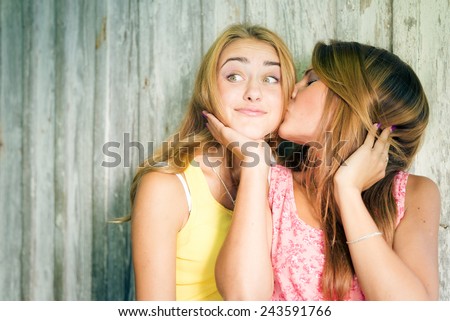 Portrait of two pretty girlfriends kissing