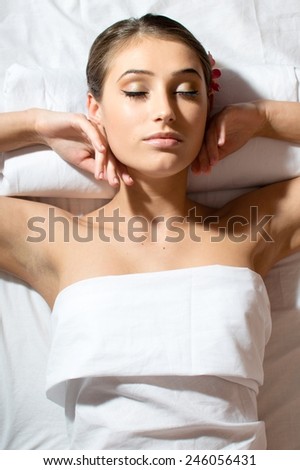 picture of relaxed beautiful young lady lying on her back and getting beauty massage enjoying treatment