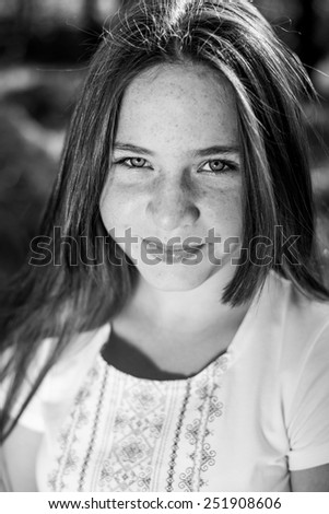 Black and white portrait of young beautiful lady with many sunspots happy smiling and wearing handmade embroidery dress