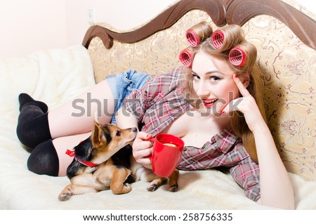 Portrait of pretty housewife at home relaxing lying in bed with cup and her dog