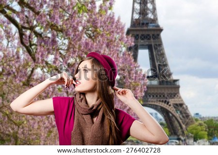 Portrait of elegant beautiful woman in hat over blurred outdoors Paris background at Eiffel tower