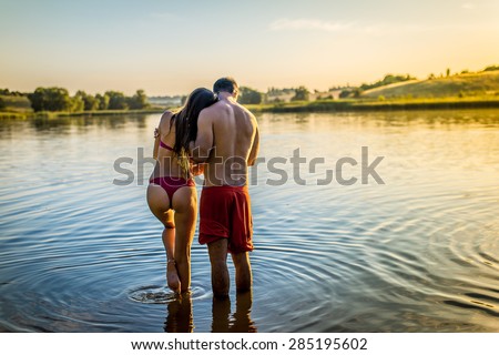 Happy romantic couple male and female having fun standing in the water on summer outdoors