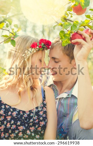 Portrait of young smiling happy couple touching their noses under apple tree in the garden outdoors