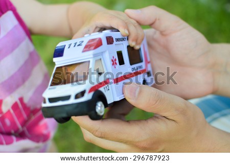 A human hand giving a toy car with the word emergency over it it to a child demonstrating concept of lifesaving