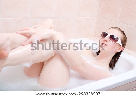 Beautiful blonde young woman lying in foam bath