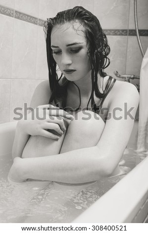 Black and white picture of  young sad woman in bath