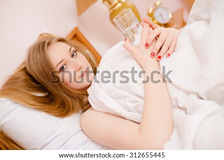 Young beautiful girl in bed holding a glass of water