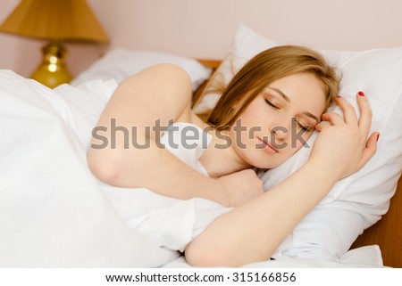 Young beautiful sleeping blonde lady lying in bed