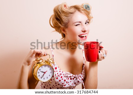Smiling housewife with alarm-clock and cup
