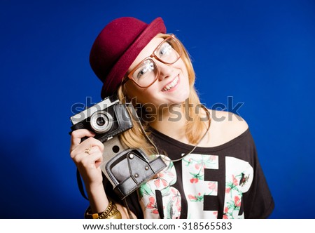 Pretty girl in hipster glasses and hat holding vintage camera