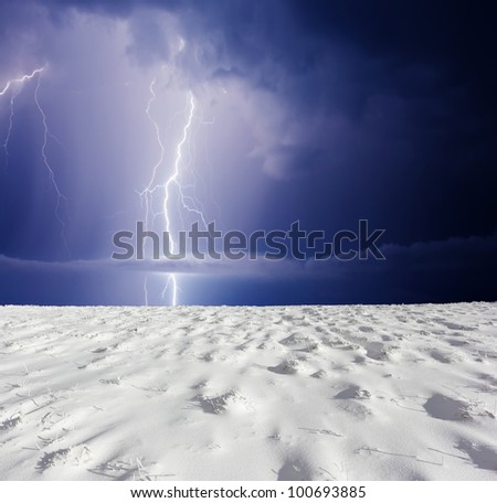 Thunderstorm with lightning in winter meadow. Dark ominous clouds.