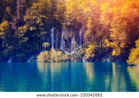 Majestic view on waterfall with turquoise water and sunny beams in Plitvice Lakes National Park. Forest glowing by sunlight. Croatia. Europe. Dramatic morning scene. Beauty world. Instagram effect.