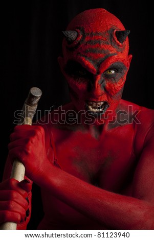 Red devil woman attacking with a hammer, low key lighting.