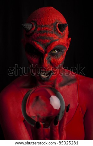 Red devil woman with her crystal ball, black background.