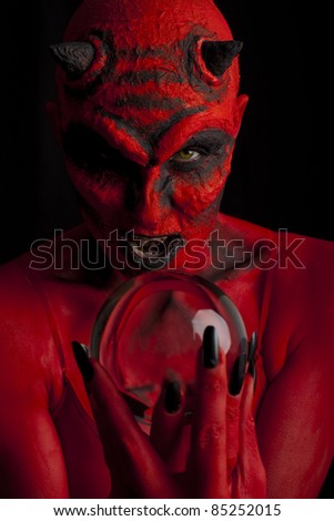 Red devil woman with her crystal ball, black background.