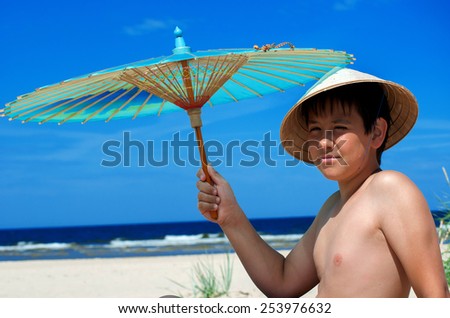 Boy with chinese umbrella on the beach