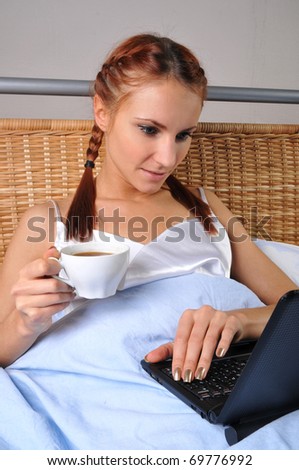 The young woman in bed at breakfast works behind the laptop