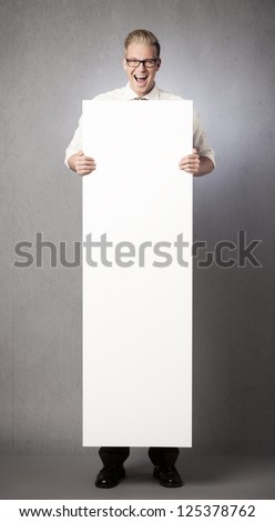 Happy laughing businessman holding white blank vertical billboard with space for text isolated on grey background.