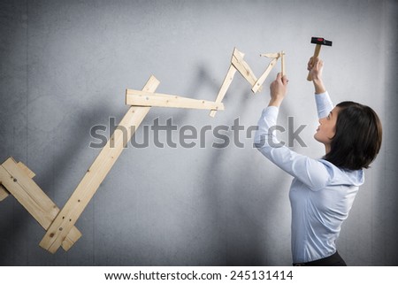 Concept: Building your own career or business. Young businesswoman installing upward arrow on floating business graph with positive trend, isolated on grey background