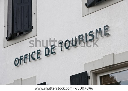 French tourism office sign on a white wall