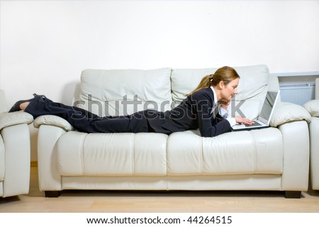Young happy woman with  laptop lying on a couch