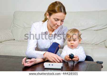 Attractive woman and her baby daughter with a blood pressure meter
