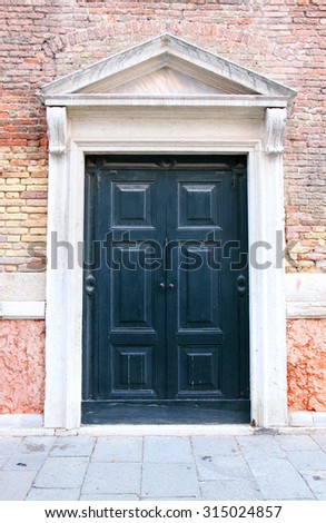 Large green wooden door set in orange brick