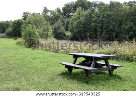 picnic table on grass near trees and lake united kingdom