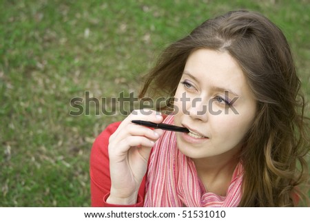 Young woman sunny day in the park thought. Biting pen