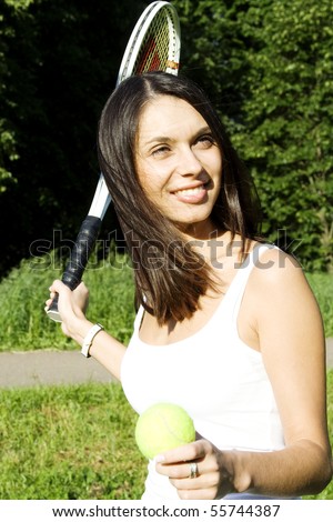 Young woman outdoors playing tennis. In the hands of the tennis racket and ball