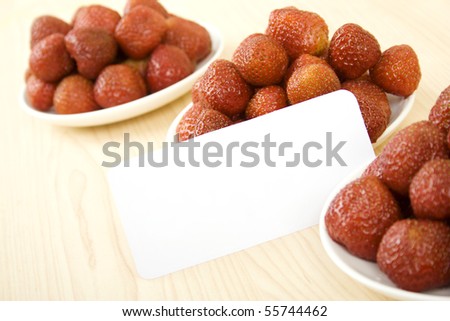 Three plates full of strawberries are on a wooden table. Near net worth Card