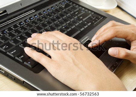 A woman\'s hands typing on a laptop.