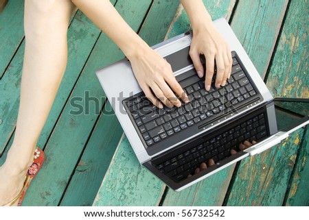 A woman\'s hands typing on a laptop.
