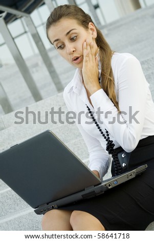 Business woman running on a laptop. He sits on the stairs office building. Expression