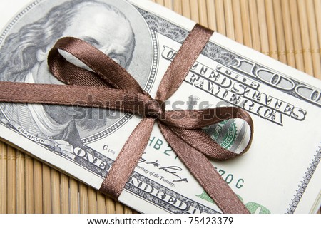 On the table there is money tied up with ribbon, diary and pen