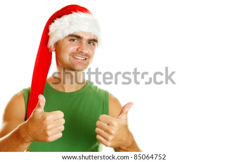 Young man in a Santa Claus hat and green poppy approvingly shows the thumb raised up. Isolated on a white background