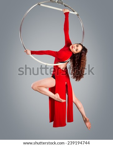 Plastic beautiful girl gymnast on acrobatic circus ring in flesh-colored suit. Aerial ring.