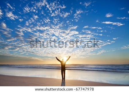 Man on the beach appreciate beautiful sunrise with his hands up