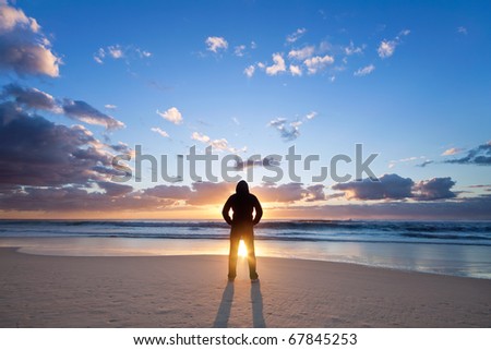 man on the beach in front of rising sun
