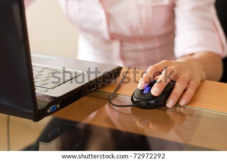 cropped image of woman who works on her laptop where her hand and mouse is shown