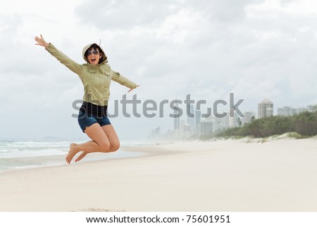 happy young woman jumps on the beach with joyful scream