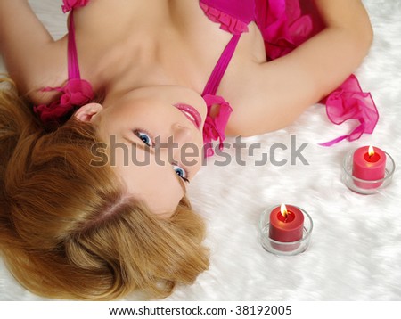 Beautiful young woman with candle, lying on fur