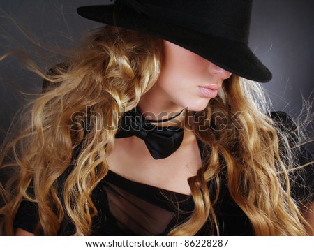 The beautiful girl with long curly hair in a black hat