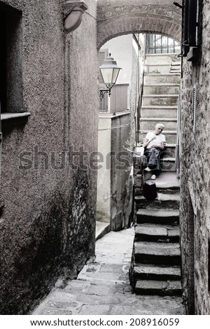 GIGLIO ISLAND, ITALY - JULY 19, 2014: Old man is resting on the stairs of the house in Ancient Village \