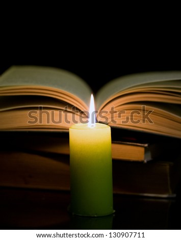 Candle and book on dark background